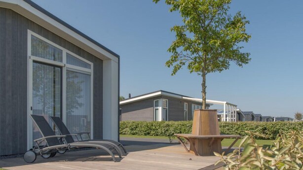 A modern house with a deck, lounge chairs, and a tree. - Holiday Home in Zeeland With Workation Setup (Wemeldinge)