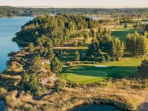 A golf course with a water body on one side and a forested area on the other. - 4 Star Holiday Home in Askersund (Askersund)