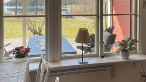 A room with a large window, a table with chairs, a radiator, and a potted plant. - 4 Star Holiday Home in Askersund (Askersund)