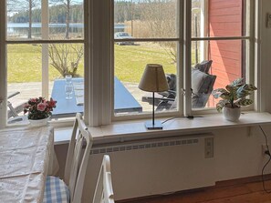A room with a large window, a table with chairs, a radiator, and a potted plant. - 4 Star Holiday Home in Askersund (Askersund)