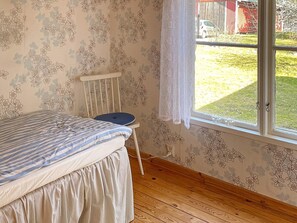 A bedroom with a bed, a chair, a window, and a view of a yard. - 4 Star Holiday Home in Askersund (Askersund)