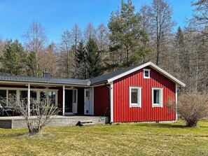 A red wooden house with a porch and a garage. - 4 Star Holiday Home in Askersund (Askersund)