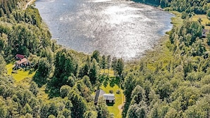 Een uitgestrekt wateroppervlak omringd door dicht bos, met in de verte enkele gebouwen.