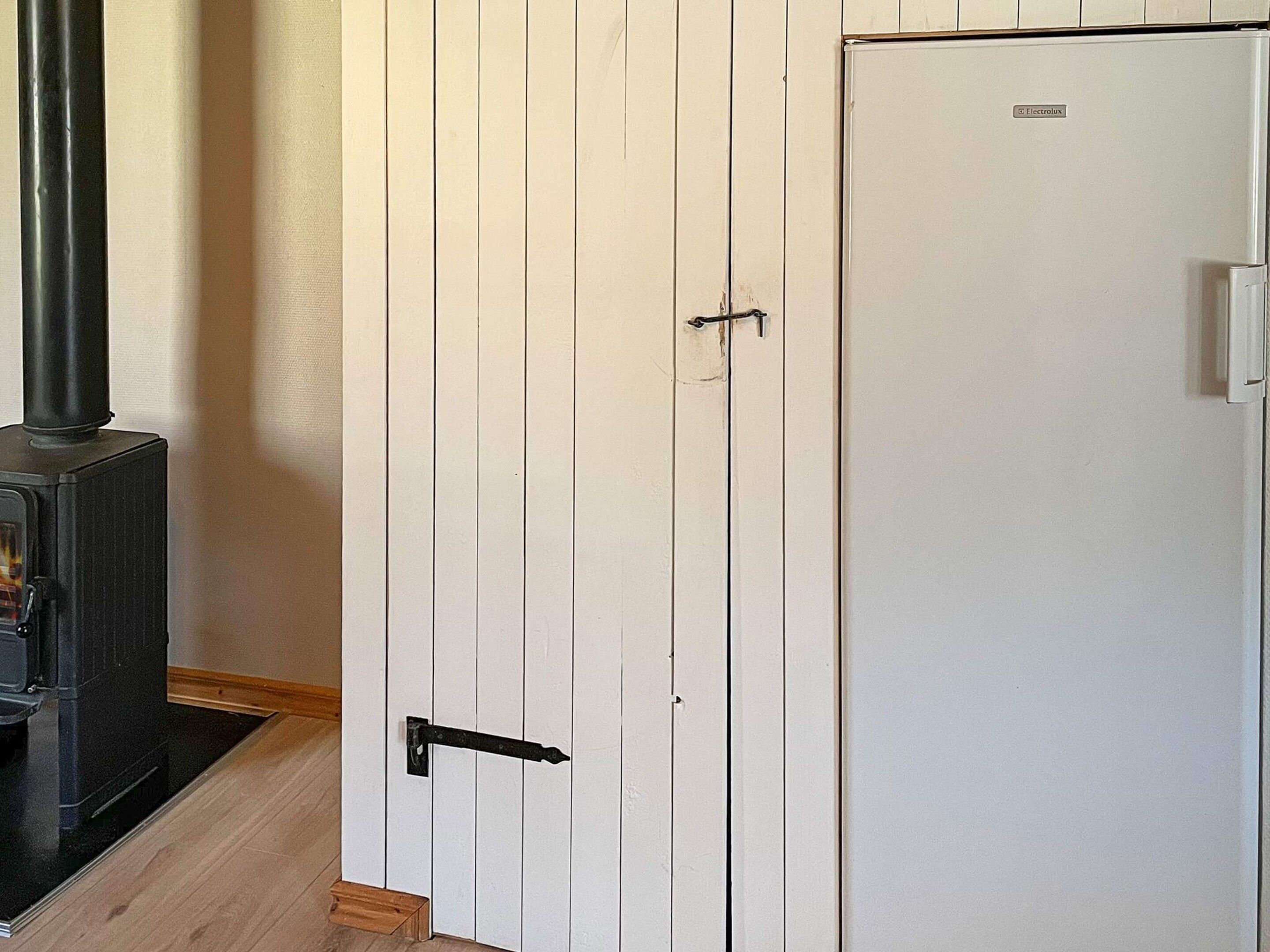 Una habitación con una puerta blanca, un calentador negro y un refrigerador blanco.