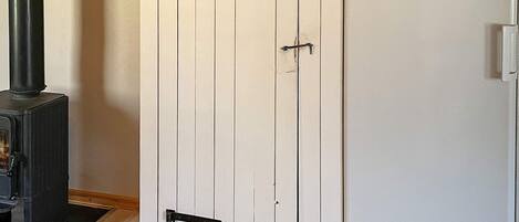 Una habitación con una puerta blanca, un calentador negro y un refrigerador blanco.
