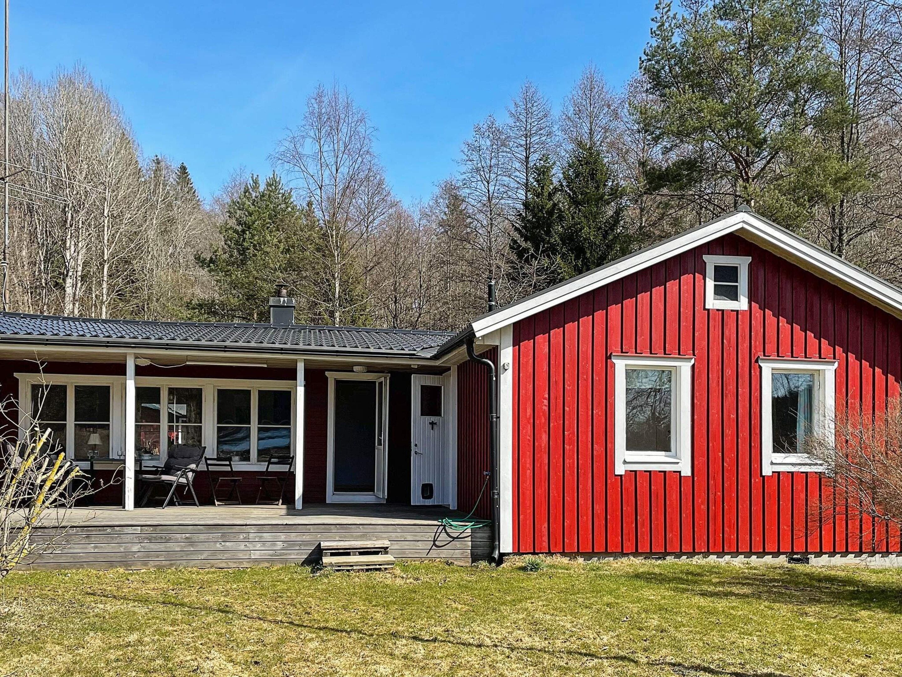 A red wooden house with a porch and a covered patio area.