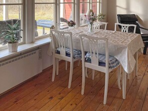 A dining area with a table set for four, white chairs, and a window with a view of the outdoors. - 4 Star Holiday Home in Askersund (Askersund)