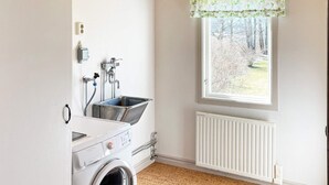 A laundry room with a washing machine, a sink, and a window with a view of trees. - 4 Star Holiday Home in Askersund (Askersund)