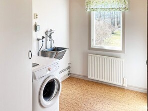 A laundry room with a washing machine, a sink, and a window with a view of trees. - 4 Star Holiday Home in Askersund (Askersund)