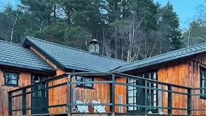 Een houten hutje met een balkon, omringd door bomen.