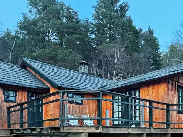 A wooden cabin with a balcony, surrounded by trees.