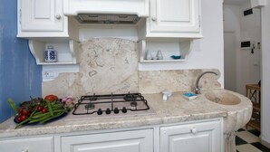 A kitchen with white cabinets, a marble countertop, a gas stove, and a sink. - Marina di Castagneto Carducci Stay (Castagneto Carducci)