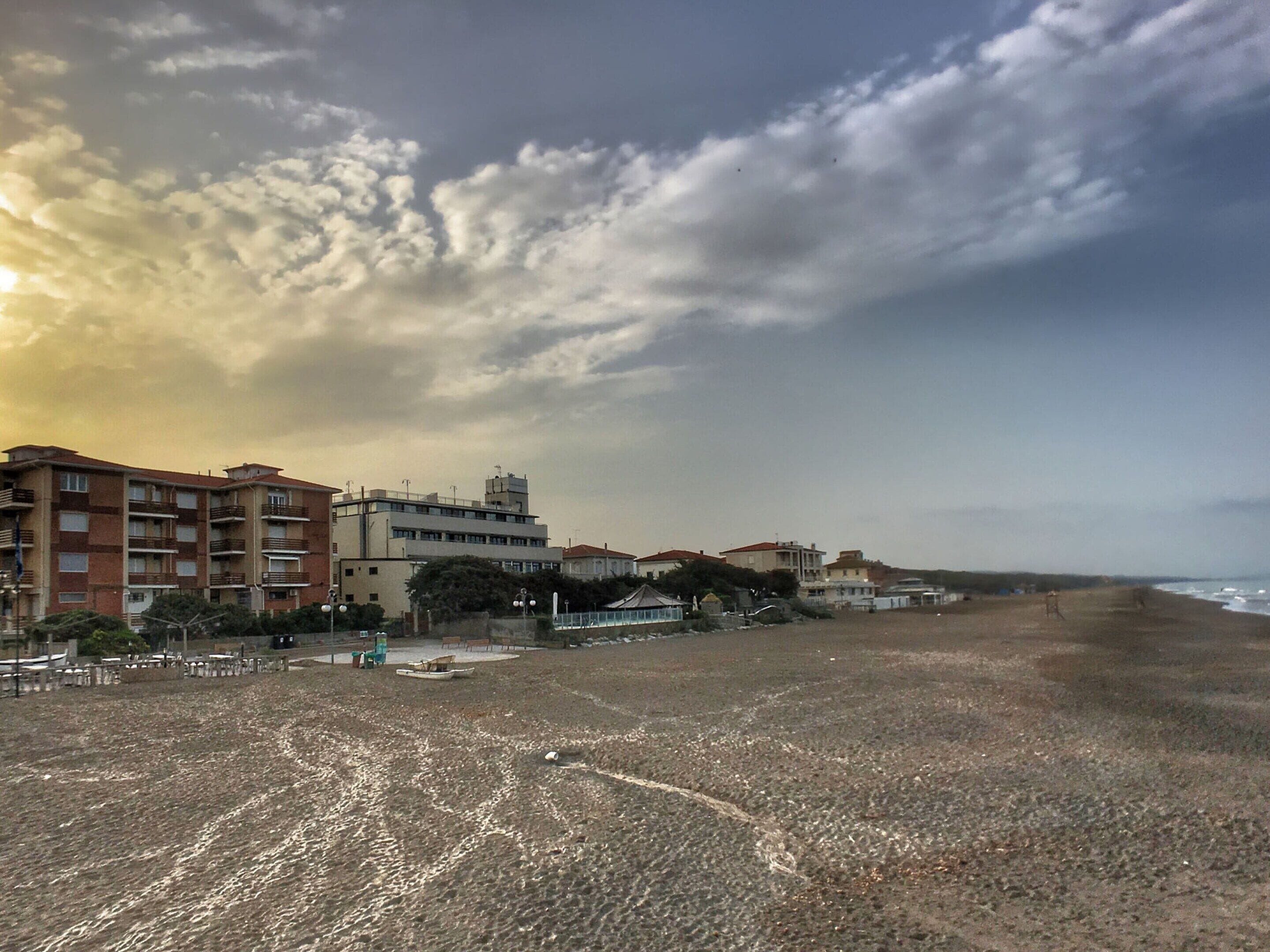 Une plage avec des bâtiments en arrière-plan, dont un immeuble à plusieurs étages doté de balcons.