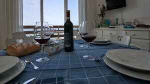 A dining table set with plates, glasses, and a bottle of wine, overlooking a balcony with a view of the sea. - Marina di Castagneto Carducci Stay (Castagneto Carducci)