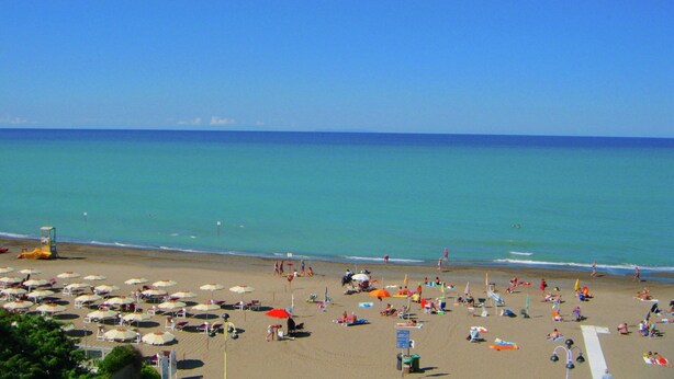 A beach with numerous umbrellas and sun loungers, a lifeguard tower, and a clear view of the ocean. - Marina di Castagneto Carducci Stay (Castagneto Carducci)