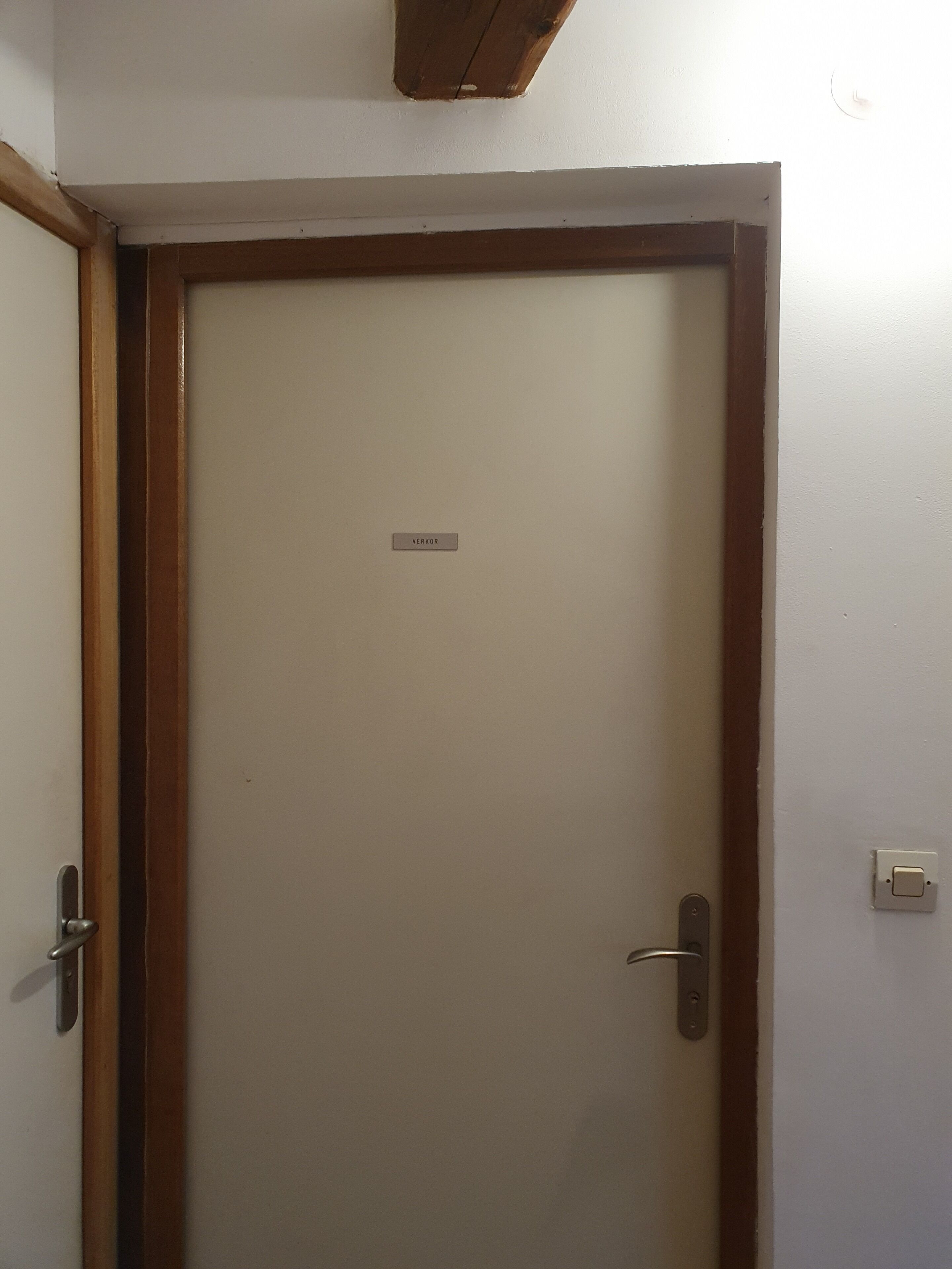 En stängd dörr med en träram och en namnskylt där det står ”VERKOR”.