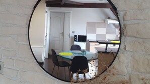 A circular mirror reflecting a dining area with a table, chairs, and a door.