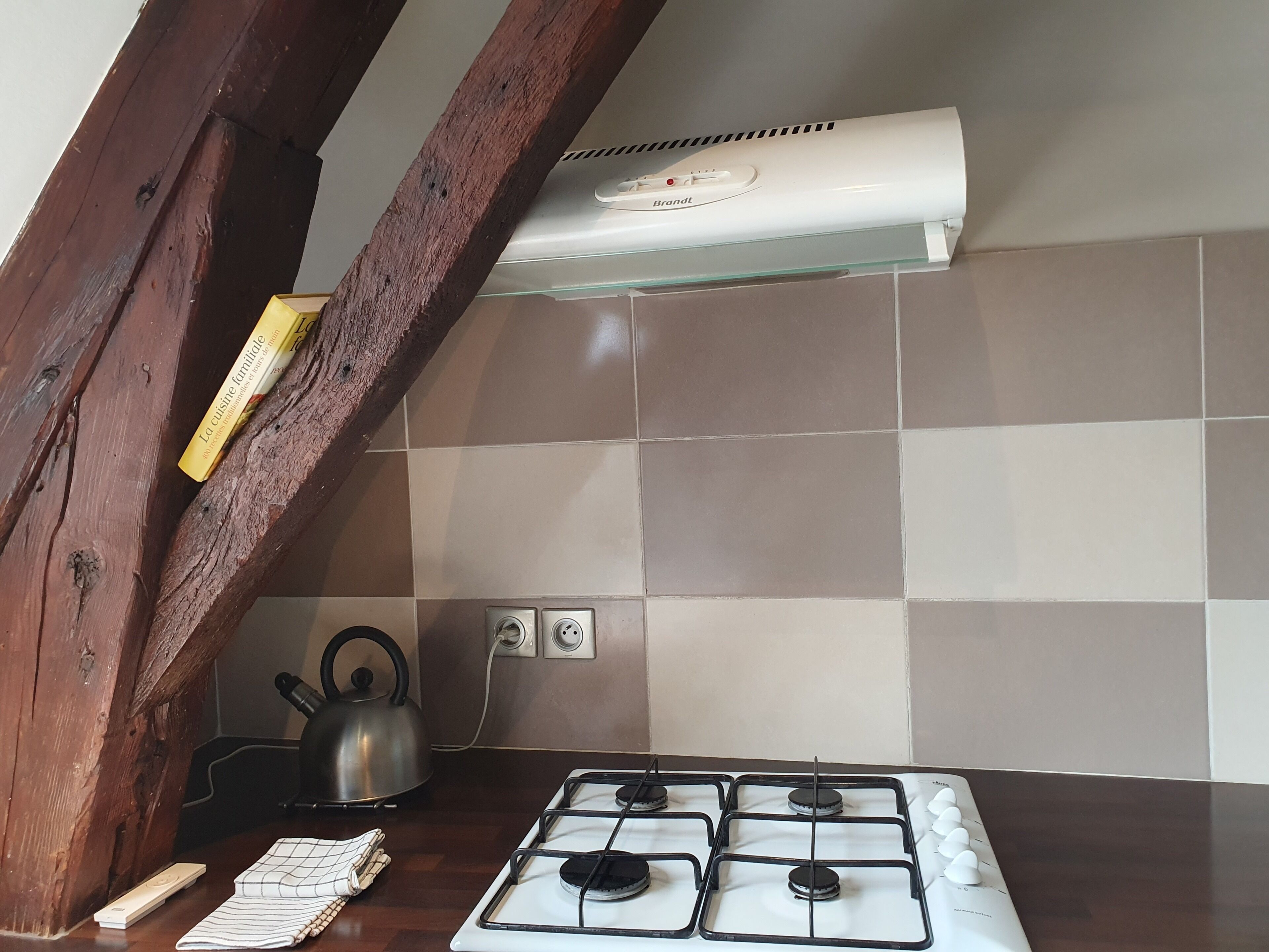 Une cuisine équipée d’une cuisinière à gaz, d’une bouilloire et d’un climatiseur blanc.