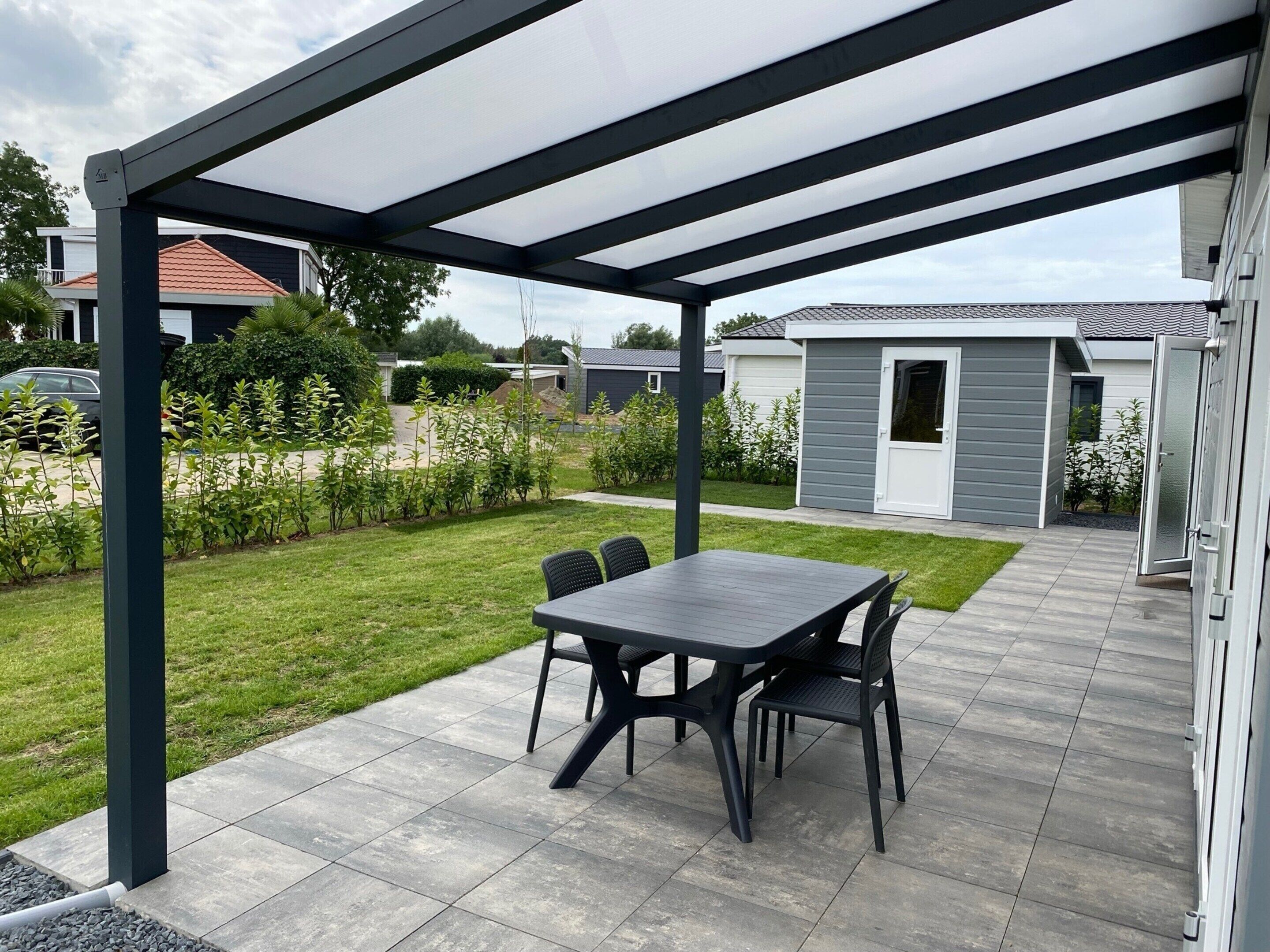 A covered patio area with a table and chairs, surrounded by a well-maintained lawn and a small shed.