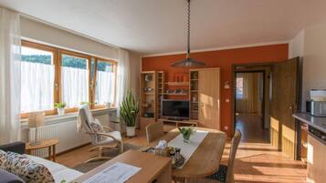 Ein gemütliches Wohnzimmer mit Esstisch, Stühlen, Fernseher und Küchenzeile.