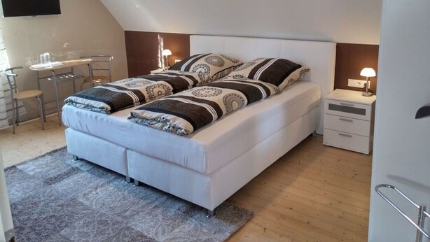 Ein modernes Schlafzimmer mit Bett, Nachttischen, einem Schreibtisch und einem Sessel.