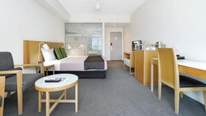 A hotel room with a bed, a desk, a chair, a small table, and a sofa. - Hotel Style Room in the heart of Darwin  (Darwin City)