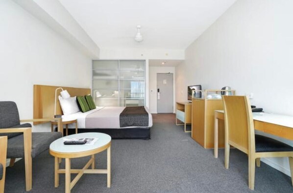 A hotel room with a bed, a desk, a chair, a small table, and a sofa. - Hotel Style Room in the heart of Darwin (Darwin City)