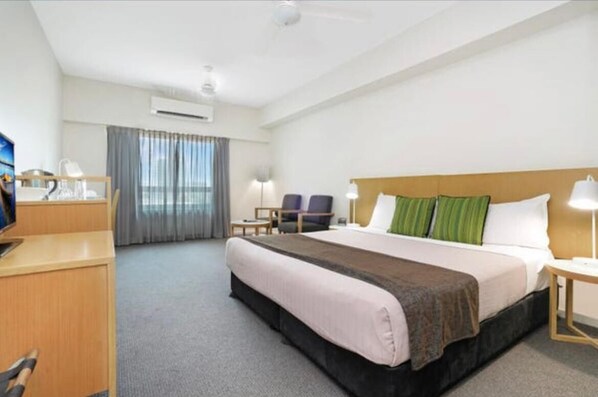 A hotel room with a bed, bedside table, lamp, desk, chair, and a television. - Hotel Style Room in the heart of Darwin (Darwin City)