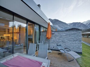 Ein moderner Sitzbereich im Freien mit einer Steinwand und Blick auf die Berge.