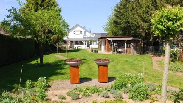 Il s’agit d’une propriété résidentielle dotée d’une pelouse bien entretenue, de deux grands jardinières et d’une maison avec un porche.