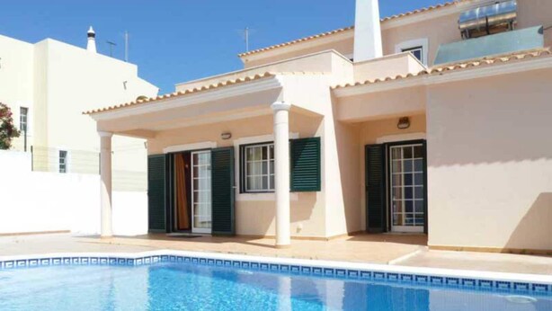 Une maison moderne dotée d’une piscine, d’un patio couvert et d’une façade blanche.