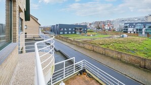 A modern building with a spiral staircase, a canal, and a view of the cityscape. - Cozy Apartment Near the Beach (Middelkerke)