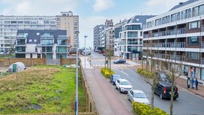 A modern urban street with multi-story residential buildings, a pedestrian crossing, and parked cars. - Cozy Apartment Near the Beach (Middelkerke)