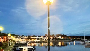 A waterfront scene with a prominent street lamp, calm water reflecting lights, and a row of houses in the background. - 4 Star Holiday Home in Helgeroa (Larvik)