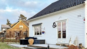A white building with a black tiled roof, a number '1131' on the side, and a front door with a wreath. - 4 Star Holiday Home in Helgeroa (Larvik)