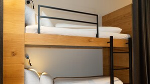 Ein Stockbett mit Holzgestell und weißer Bettwäsche.