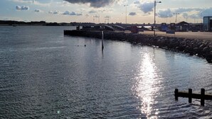 A calm waterfront with a pier extending into the water, surrounded by a rocky shoreline and a clear sky. - 4 Star Holiday Home in Faaborg (Faaborg)