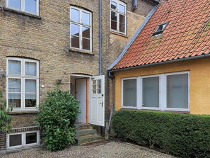 A two-story brick building with a red-tiled roof, a small front garden, and a hedge. - 4 Star Holiday Home in Faaborg (Faaborg)
