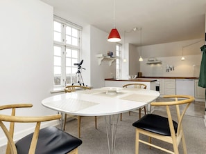 Una cocina moderna con armarios blancos, una mesa de comedor con sillas y una lámpara colgante roja.
