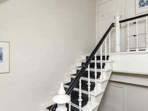 A staircase with white balusters and a black handrail, leading to a landing with a white door. - 4 Star Holiday Home in Faaborg (Faaborg)