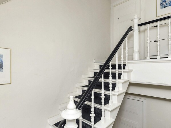 A staircase with white balusters and a black handrail, leading to a landing with a white door. - 4 Star Holiday Home in Faaborg (Faaborg)