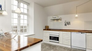 A modern kitchen with white cabinetry, a wooden countertop, a built-in oven, and a dishwasher. - 4 Star Holiday Home in Faaborg (Faaborg)