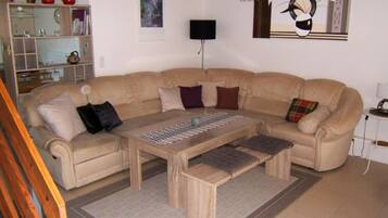 A living room with a beige sectional sofa, a wooden coffee table, and a patterned rug.