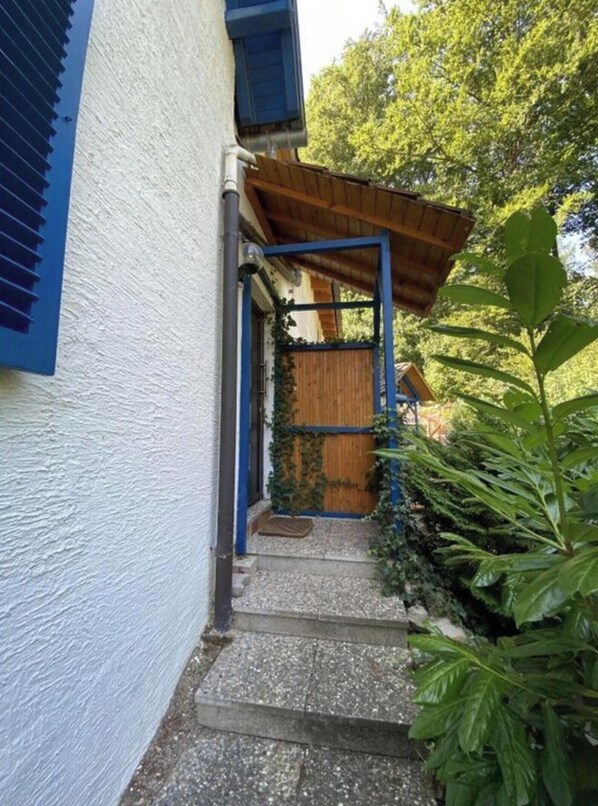 A narrow pathway leading to a wooden door, flanked by a white wall and a blue window frame. - Idyllic Holiday Home (Wachenheim an der Weinstrasse)