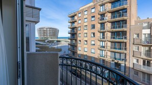 Un immeuble de grande hauteur doté de nombreux balcons et d’une structure sphérique distinctive en arrière-plan.