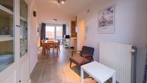 Un vaste espace de vie comprenant une table à manger, des chaises, une table blanche et un radiateur.