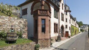 A historic building with a stone facade, arched windows, and a turret. - Holiday Apartment Riesling (Lorch)