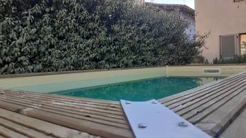 En swimmingpool med ett trädäck och ett metallräcke.