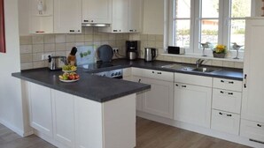 A modern kitchen with white cabinets, a black countertop, and a window with a view of the outdoors. - Holiday Home Wiedblick (Rerik)