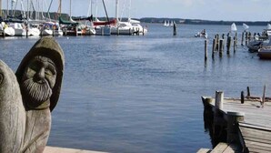 A marina with multiple boats docked, a wooden pier, and a stone sculpture. - Holiday Home Wiedblick (Rerik)